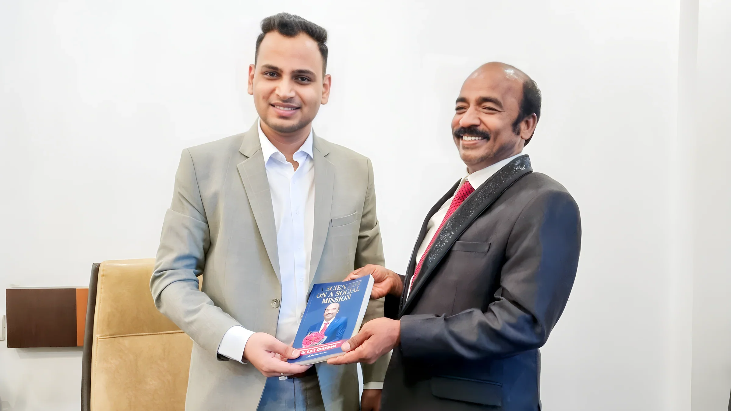 Lithvik Mukesh Sharma is photographed at his private office, jointly holding a book titled "A SCIENTIST ON A SOCIAL MISSION".